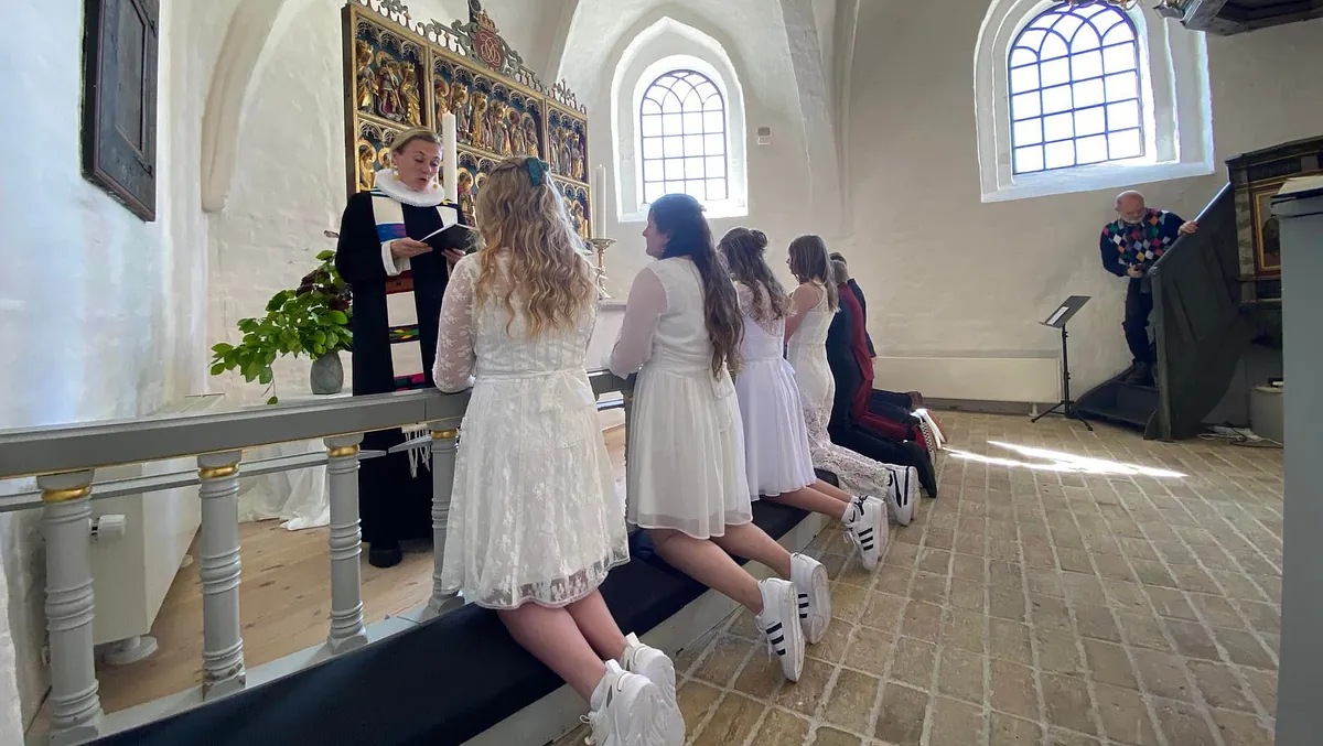 Et billede af unge piger, der knæler foran alteret til konfirmation